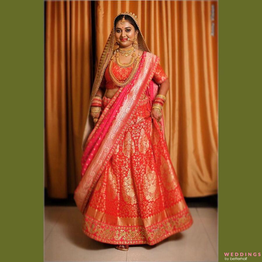 A stunning South Indian bride poses in a vibrant coral lehenga.