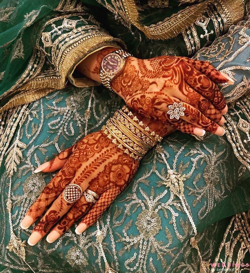 Photo of backhands floral mehndi design with exquisite wedding rings, and bangles.