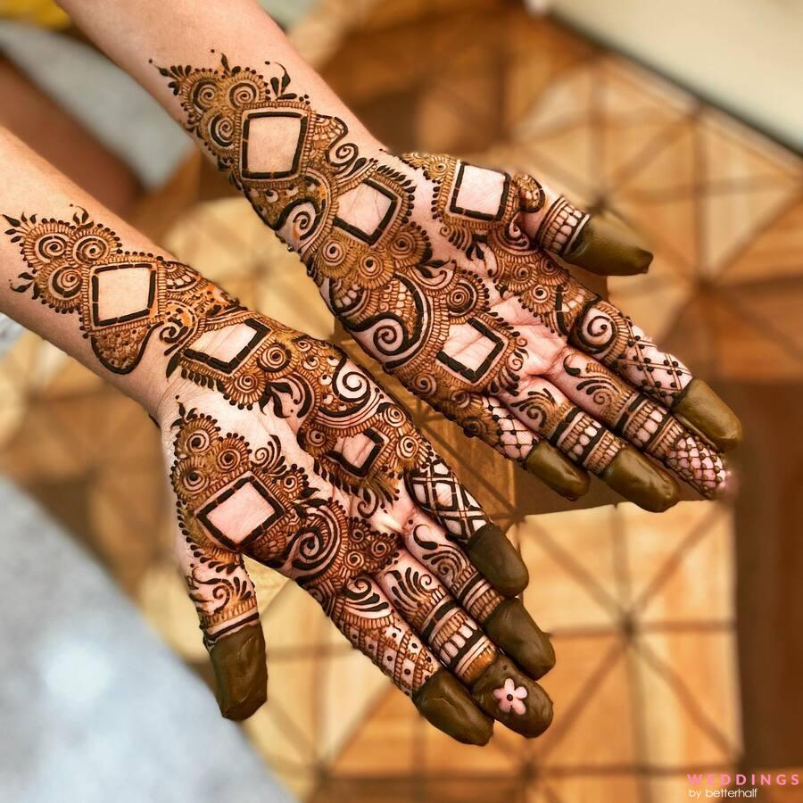 Bridal hands with detailed mehndi, geometric and floral patterns, in brown henna