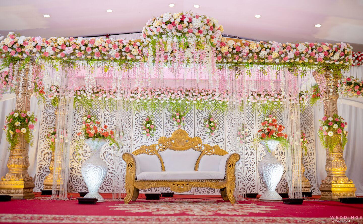 A beautifully decorated wedding venue with a focal point on a white and gold chair on the stage. Perfect for a Lavender and White-themed wedding.