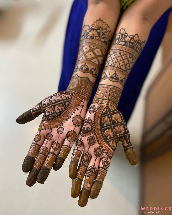 Two beautifully decorated hands showcase intricate Arabic mehndi designs in a captivating blue dress.