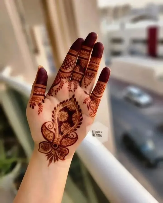 Photo of dark red mehndi desing on front hand